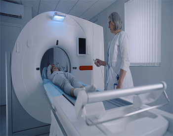 Professional radiologist lays female patient in MRI or CT or PET scan machine. Doctor conducts check up procedure in clinic with advanced medical technologies. High-tech modern medical equipment.